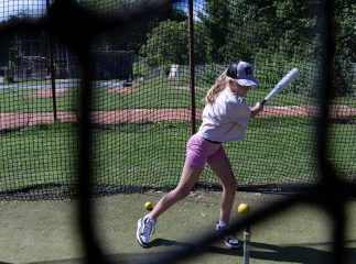 ein Mädchen schwenkt Baseballschläger und will einen Ball treffen auf dem Baseballfeld